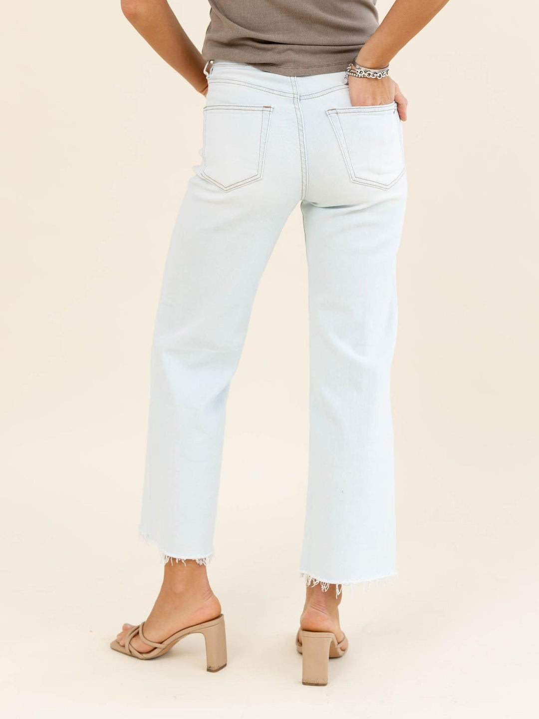 Light blue jeans worn by a person on a beige background