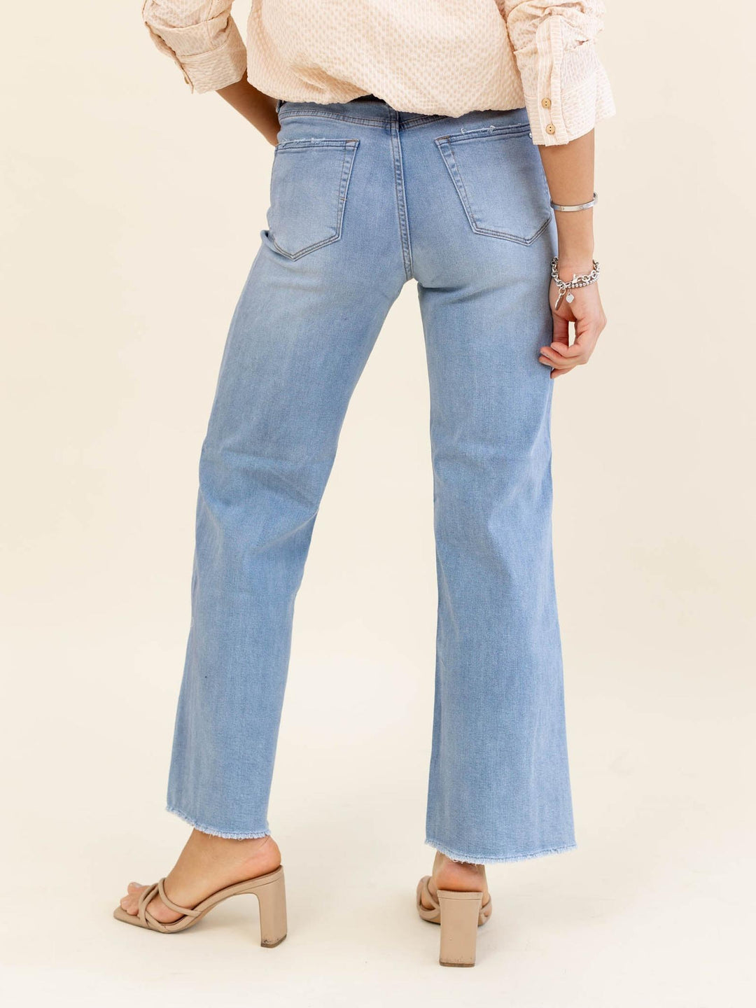 Light blue jeans worn by a person on a beige background