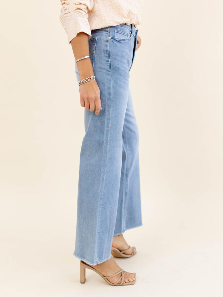 Light blue jeans worn by a person on a beige background