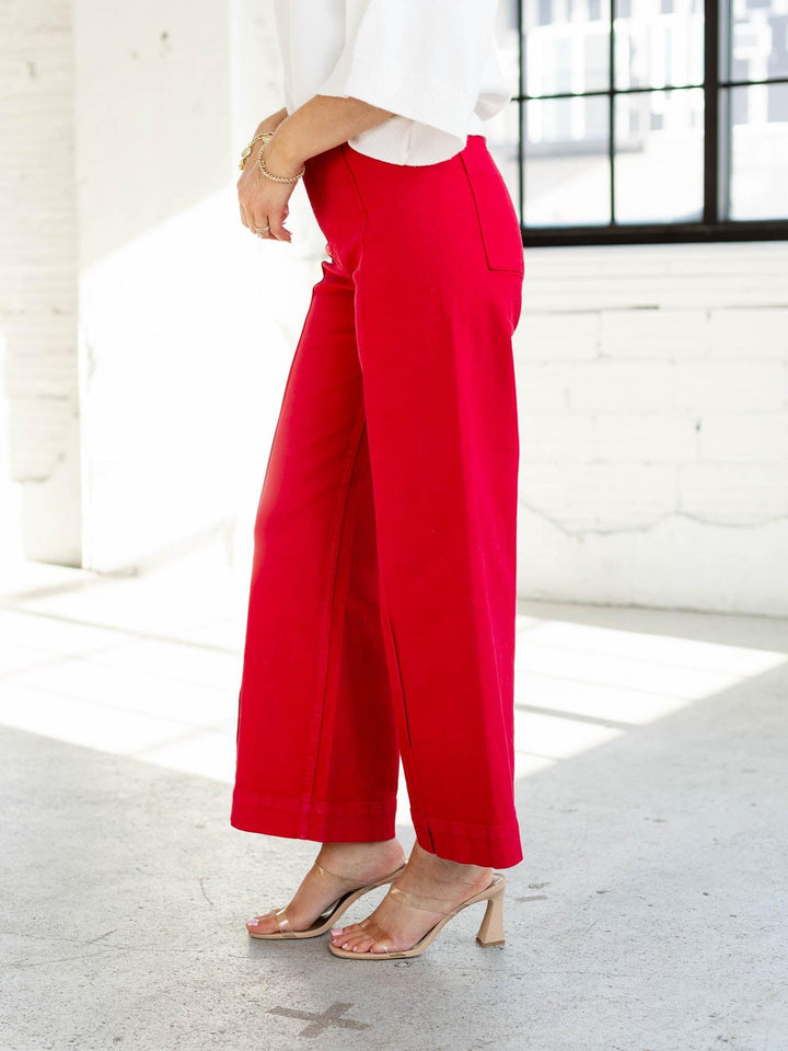 Person wearing red pants and a white top in a bright room.