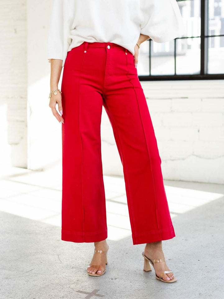 Person wearing red pants and a white top in a bright room.