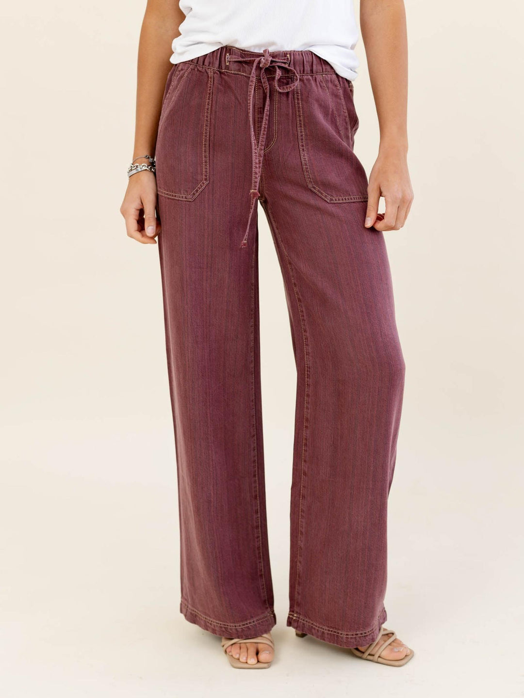 Person wearing maroon wide-leg pants with a white top on a beige background