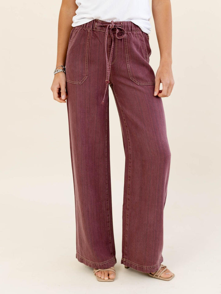 Person wearing maroon wide-leg pants with a white top on a beige background