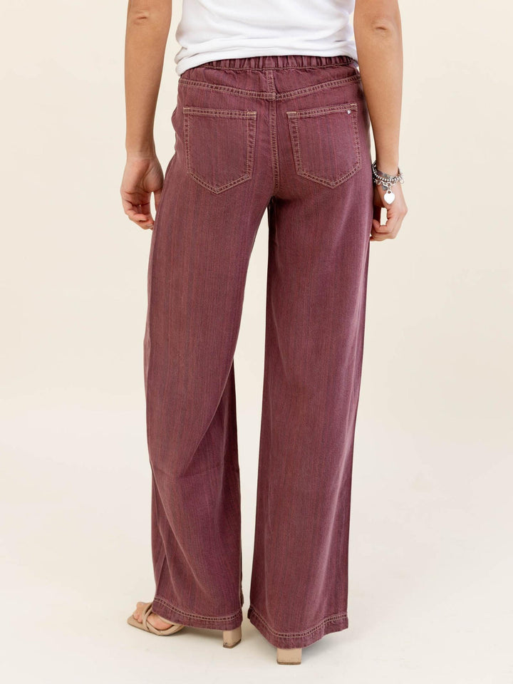 Person wearing maroon wide-leg pants on a beige background