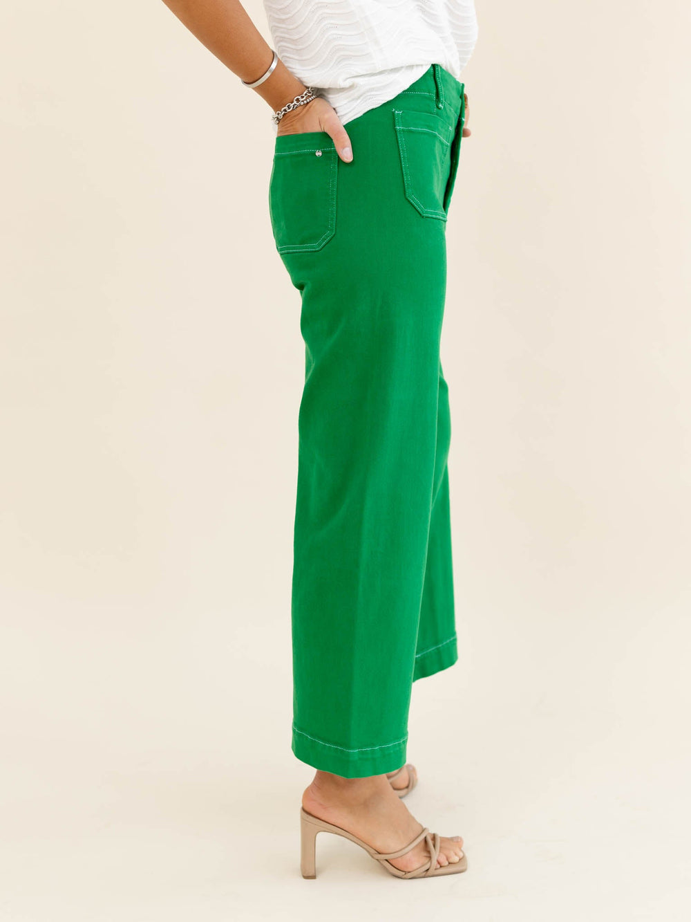 Green pants worn by a person on a beige background