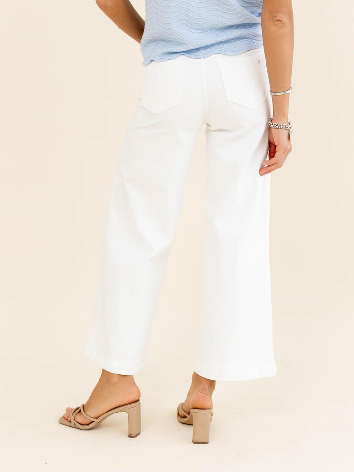 Person wearing white pants and a light blue top on a beige background