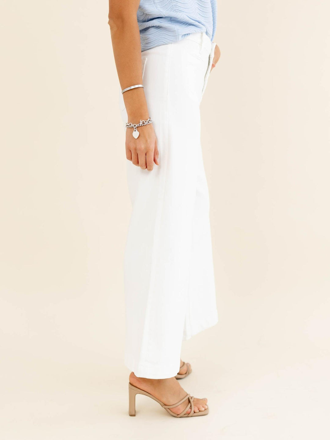 Person wearing white pants and a light blue top on a beige background
