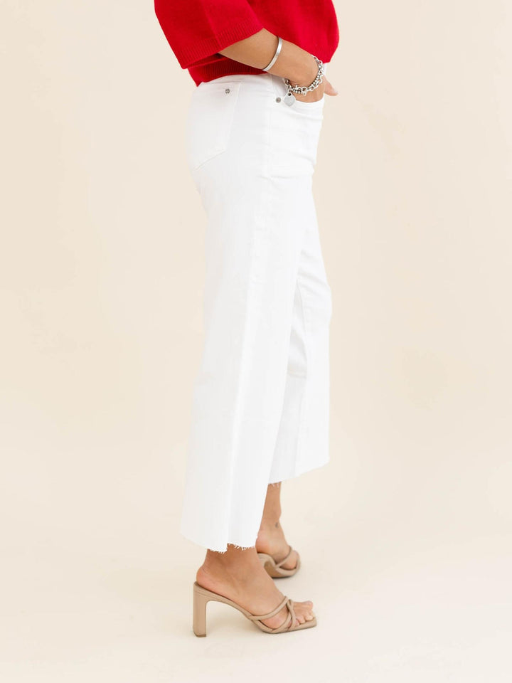 Person wearing white jeans and a red top on a beige background