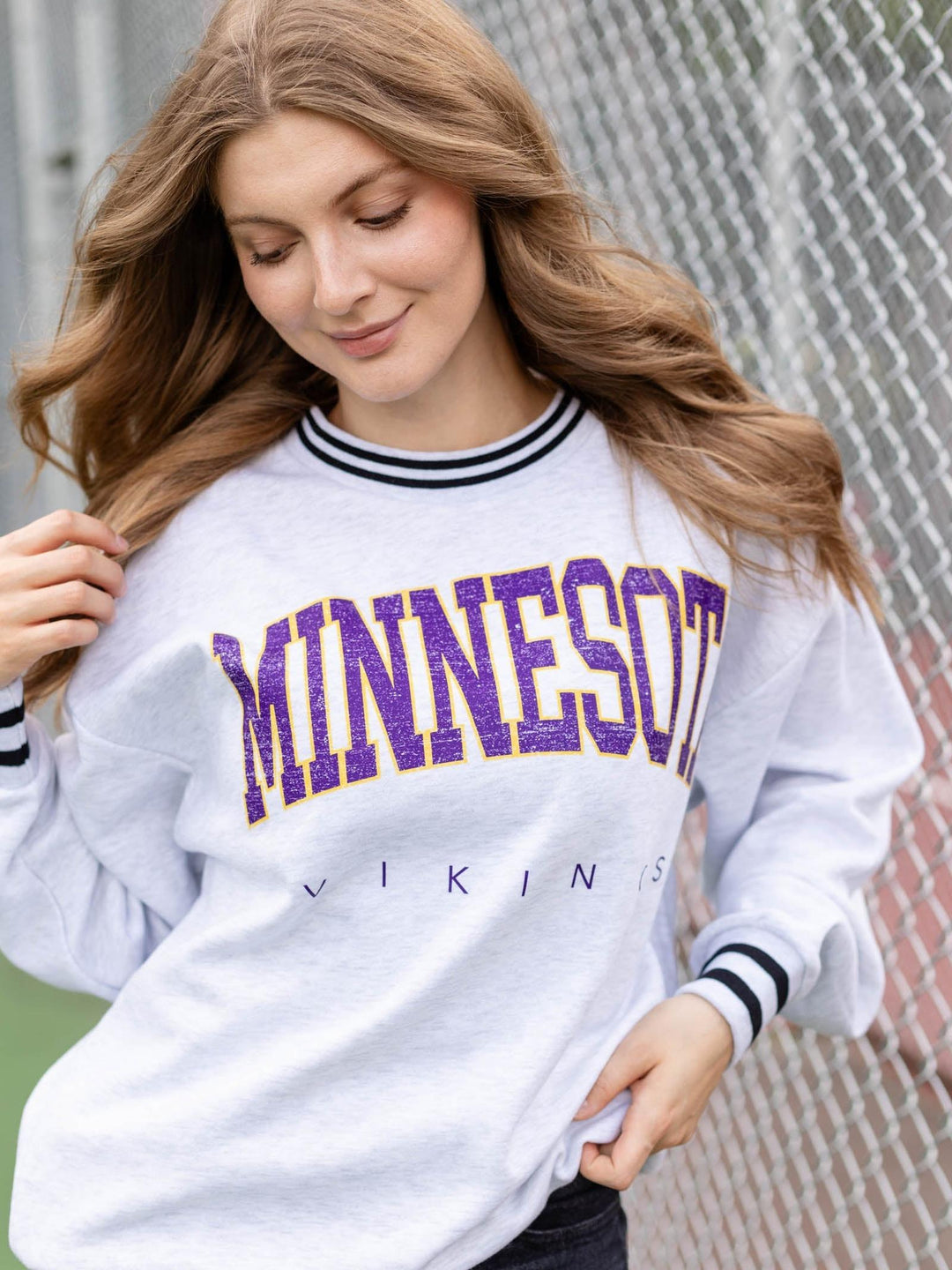A woman wearing a white long-sleeve crewneck sweatshirt with &