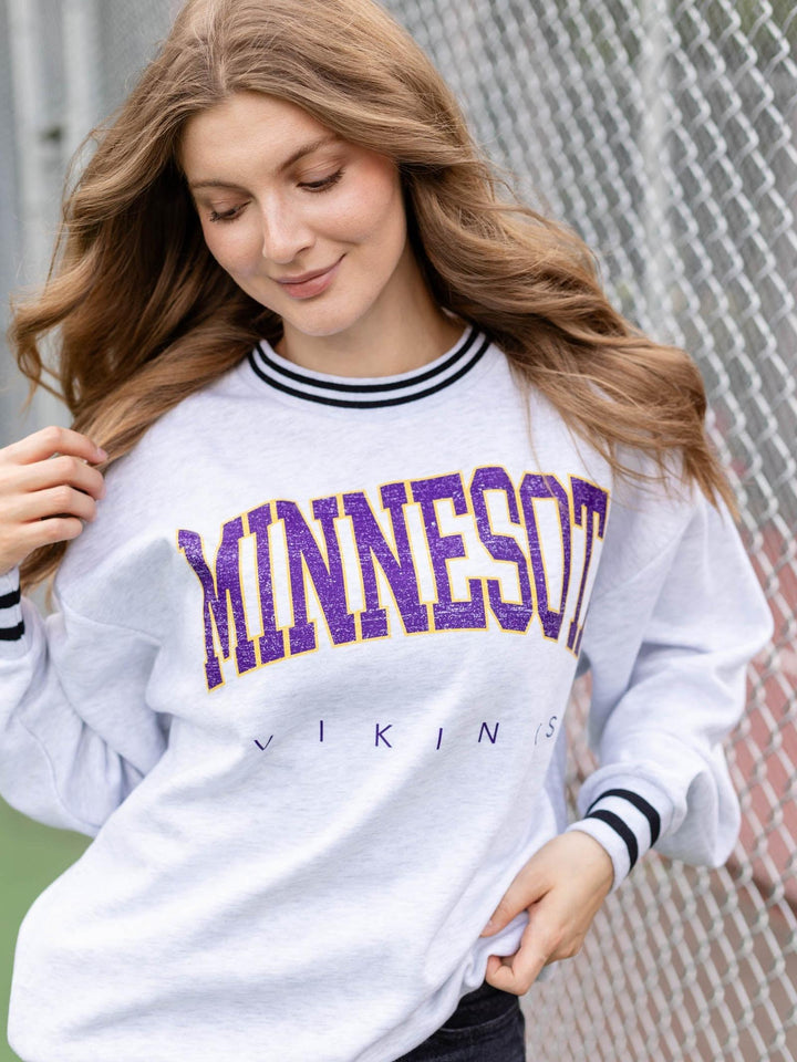 A woman wearing a white long-sleeve crewneck sweatshirt with &