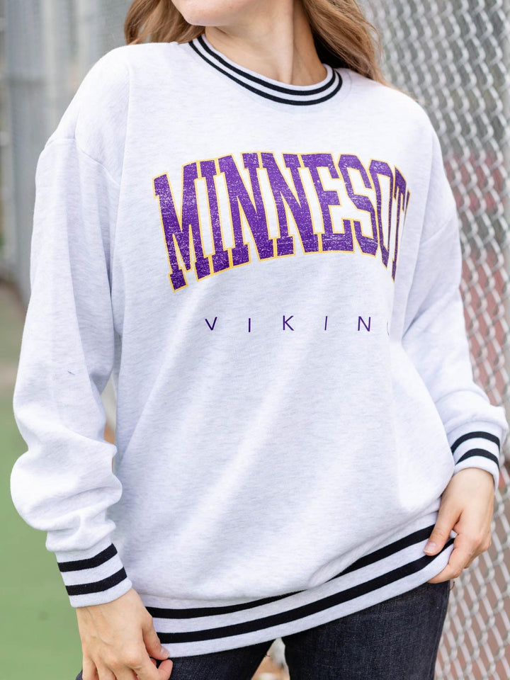 A person wearing a white long-sleeve sweatshirt with &