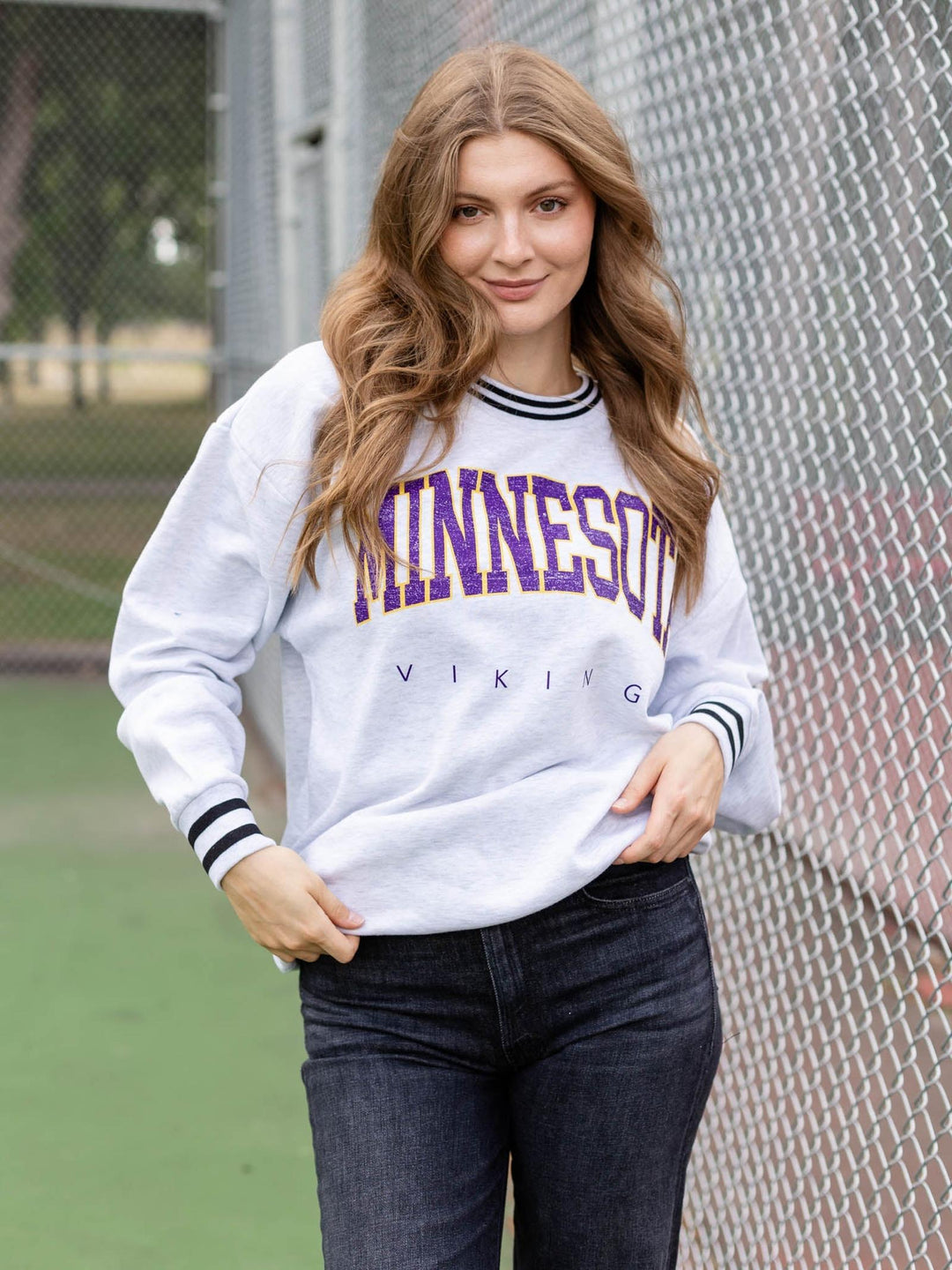 A woman wearing a white long-sleeve sweatshirt with purple and black &