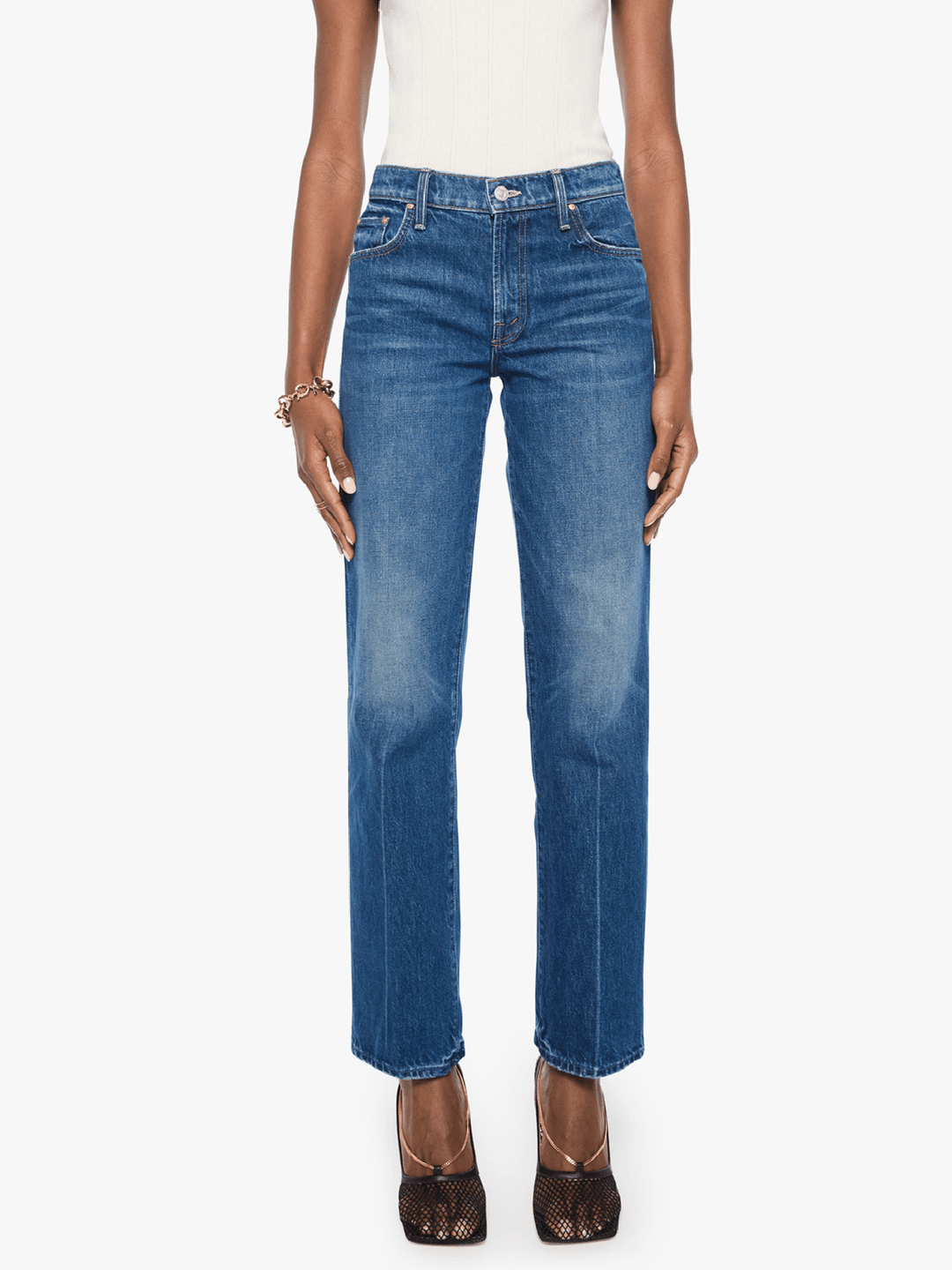 A model wearing a pair of medium-wash blue straight-leg jeans, styled with a white top and brown lace-up heels against a plain white background.
