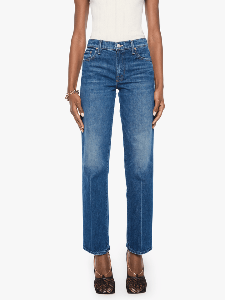 A model wearing a pair of medium-wash blue straight-leg jeans, styled with a white top and brown lace-up heels against a plain white background.