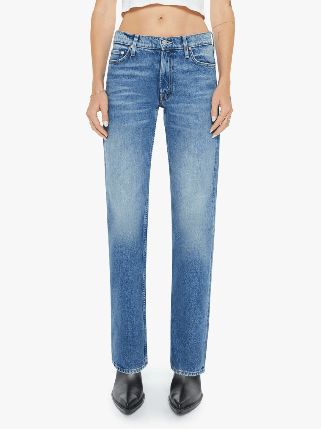 A model wearing a pair of medium-wash blue denim jeans with a subtle vertical fade, paired with black pointed-toe boots against a plain white background.