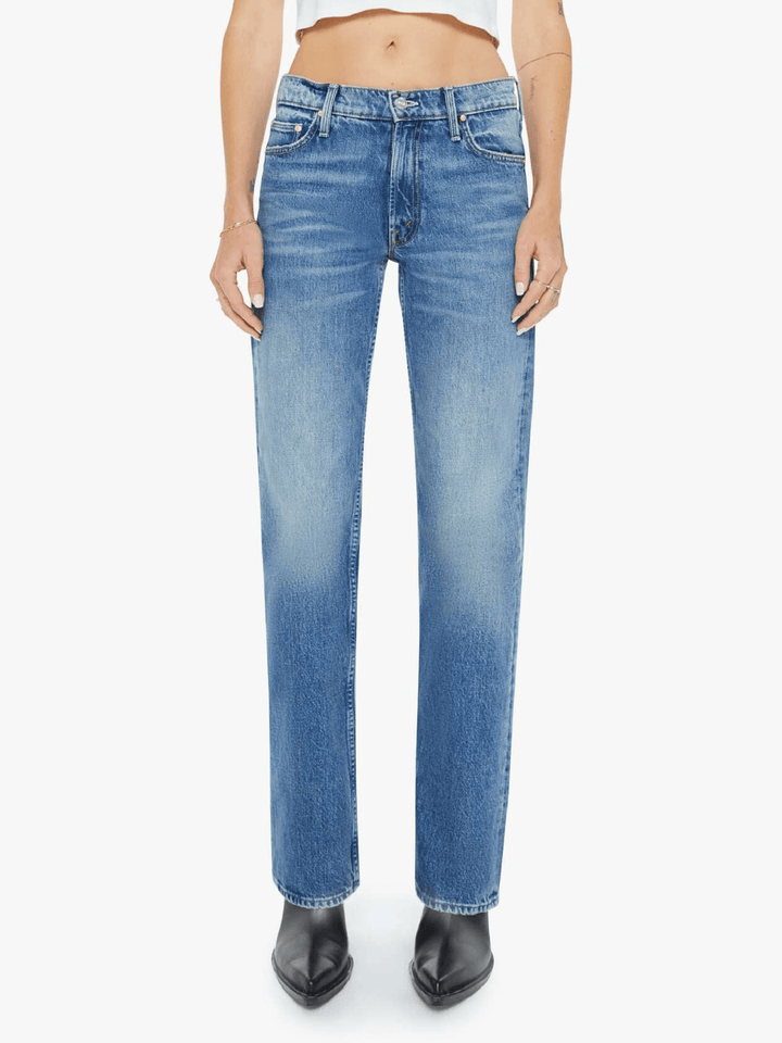 A model wearing a pair of medium-wash blue denim jeans with a subtle vertical fade, paired with black pointed-toe boots against a plain white background.