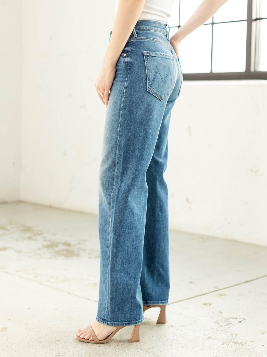 Person wearing blue jeans in a minimal indoor setting