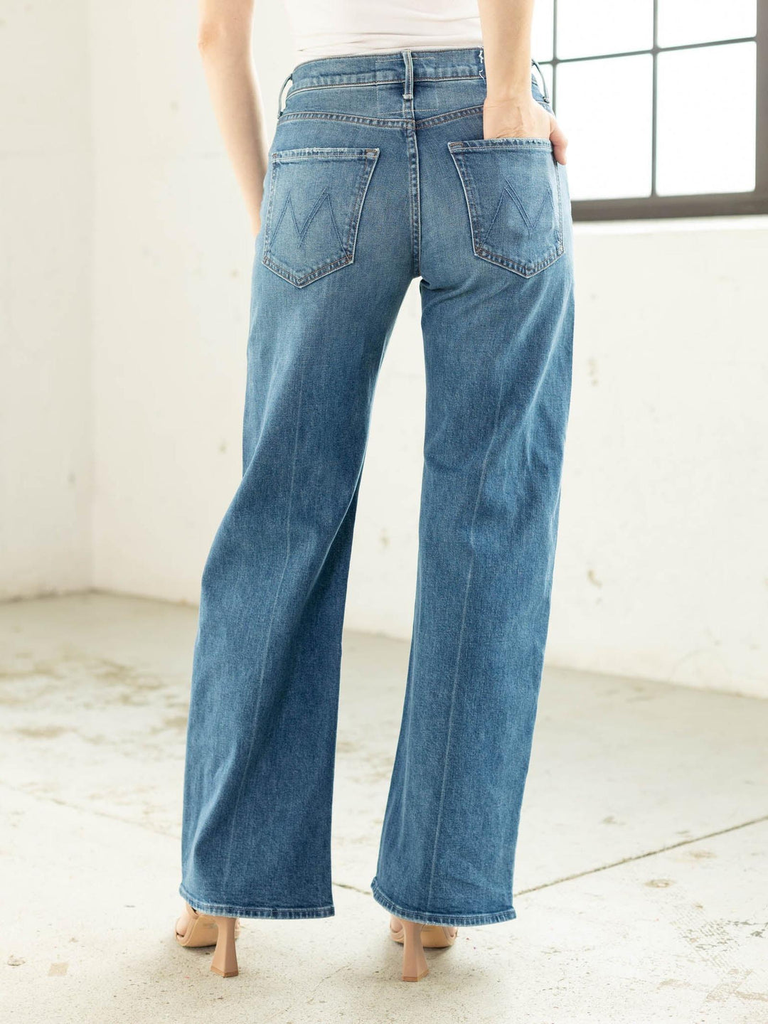 Person wearing blue jeans in a minimal indoor setting