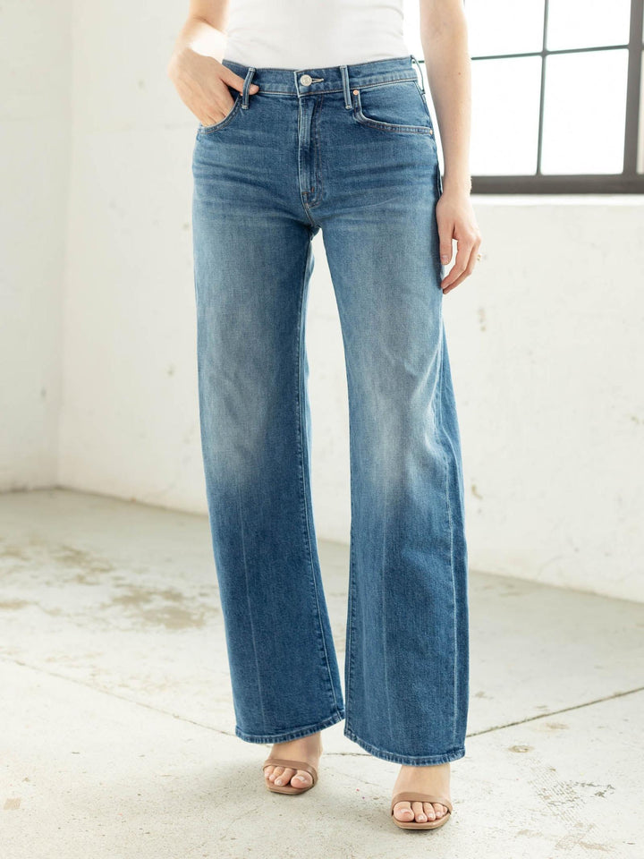 Person wearing blue jeans in a minimal indoor setting