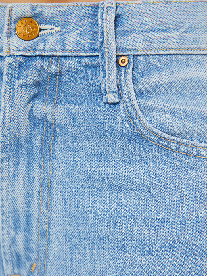 Close-up of blue denim jeans with a brand logo on the button.
