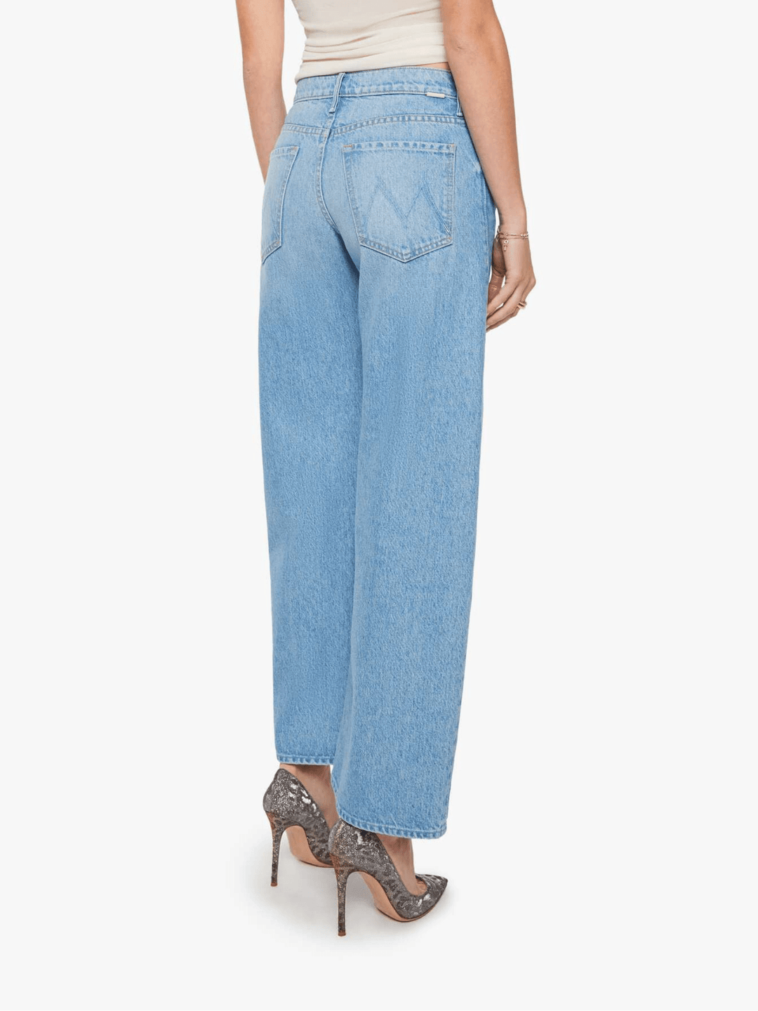 A model shown from the back wearing light-wash blue wide-leg jeans, a beige top, and gray high-heeled shoes against a plain white background.