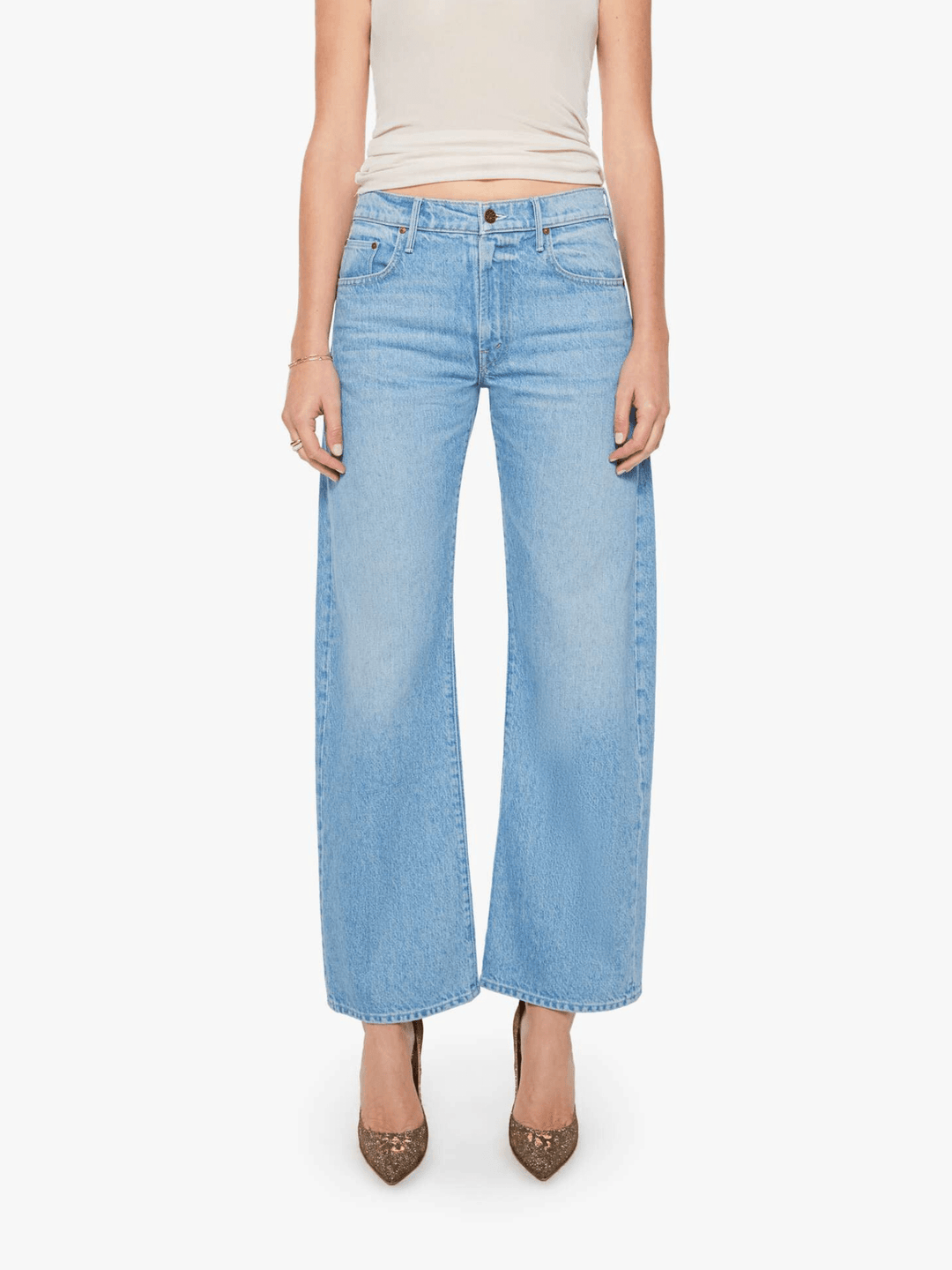 A model wearing light-wash blue wide-leg cropped jeans, paired with a beige ribbed tank top and brown pointed-toe heels, against a plain white studio background.