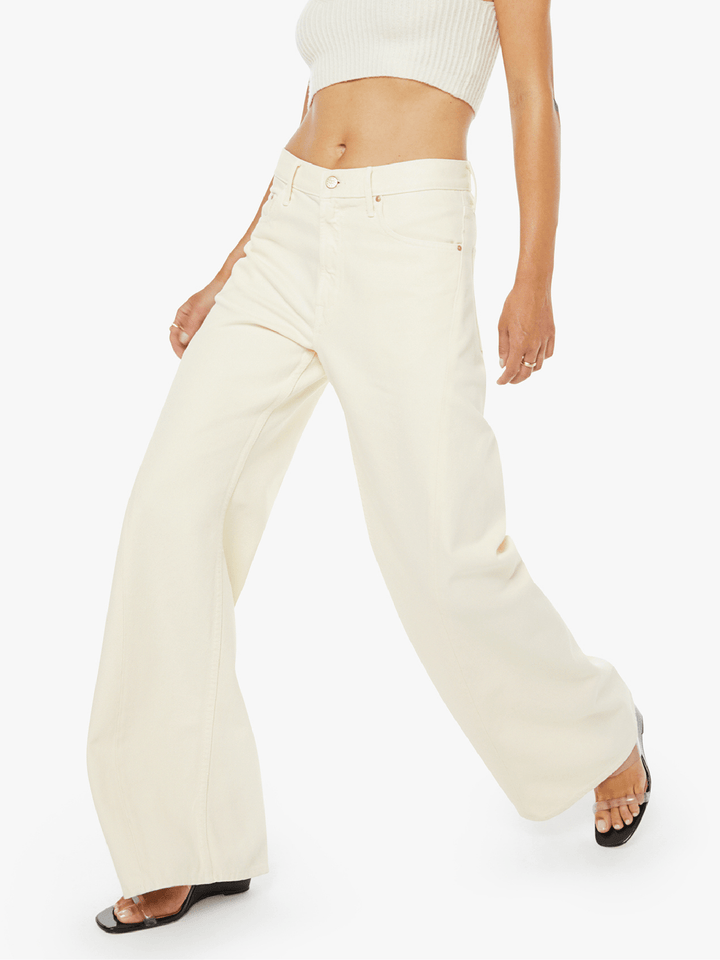 Person wearing cream-colored flared pants on a white background