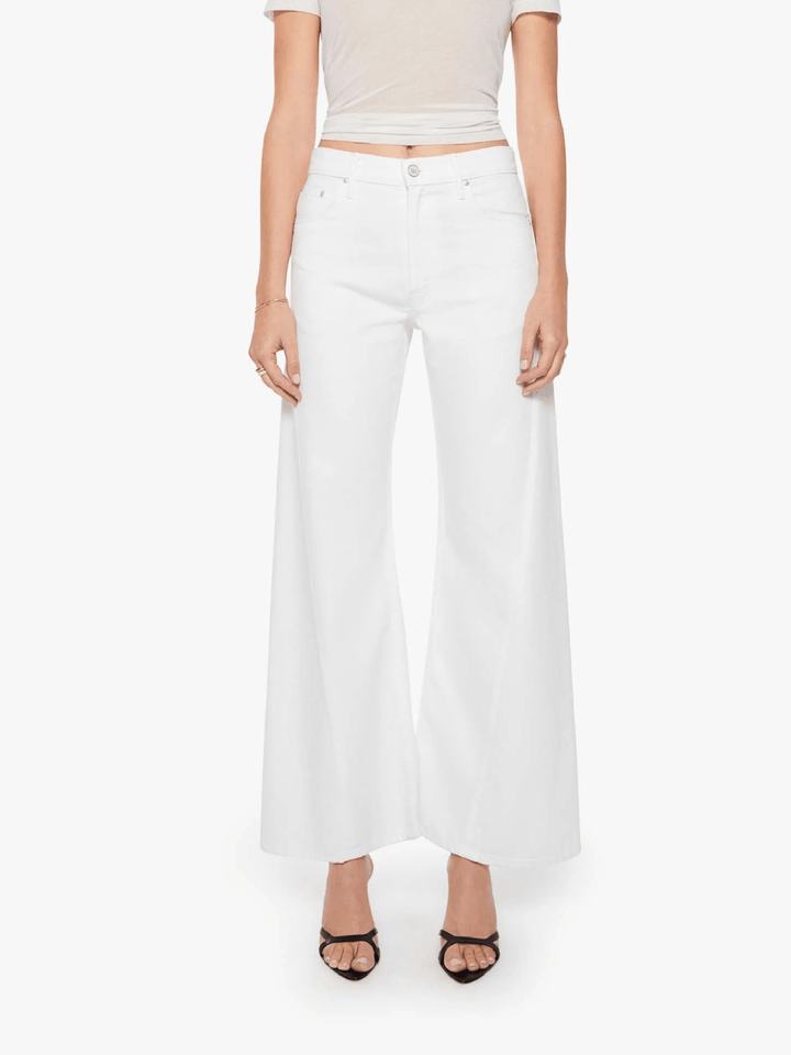 A model wearing white wide-leg cropped pants with a beige crop top and black strappy heels, shown against a plain light gray studio background.