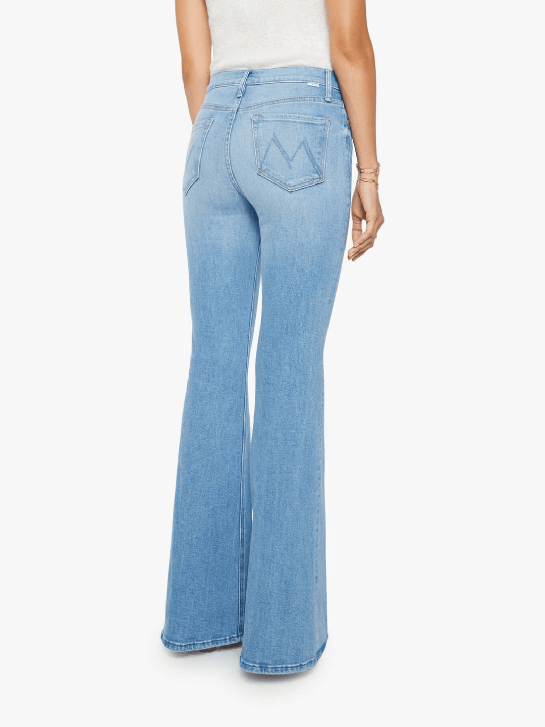 A person shown from the back wearing light blue high-waisted flare jeans, photographed against a plain light gray studio background.