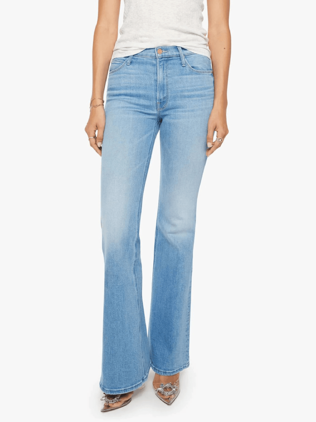 A model wearing light-wash blue flare jeans, paired with a white top and pointed shoes, shown against a plain white background.