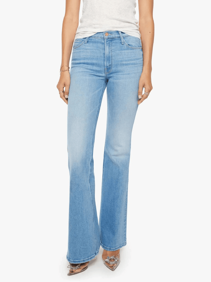 A model wearing light-wash blue flare jeans, paired with a white top and pointed shoes, shown against a plain white background.