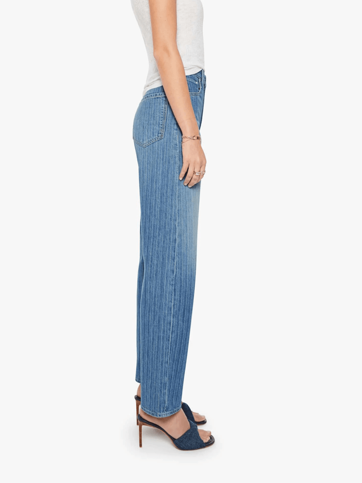 A side profile view of a model wearing light blue wide-leg denim jeans, a white sleeveless top, and navy blue heeled sandals against a plain white background.