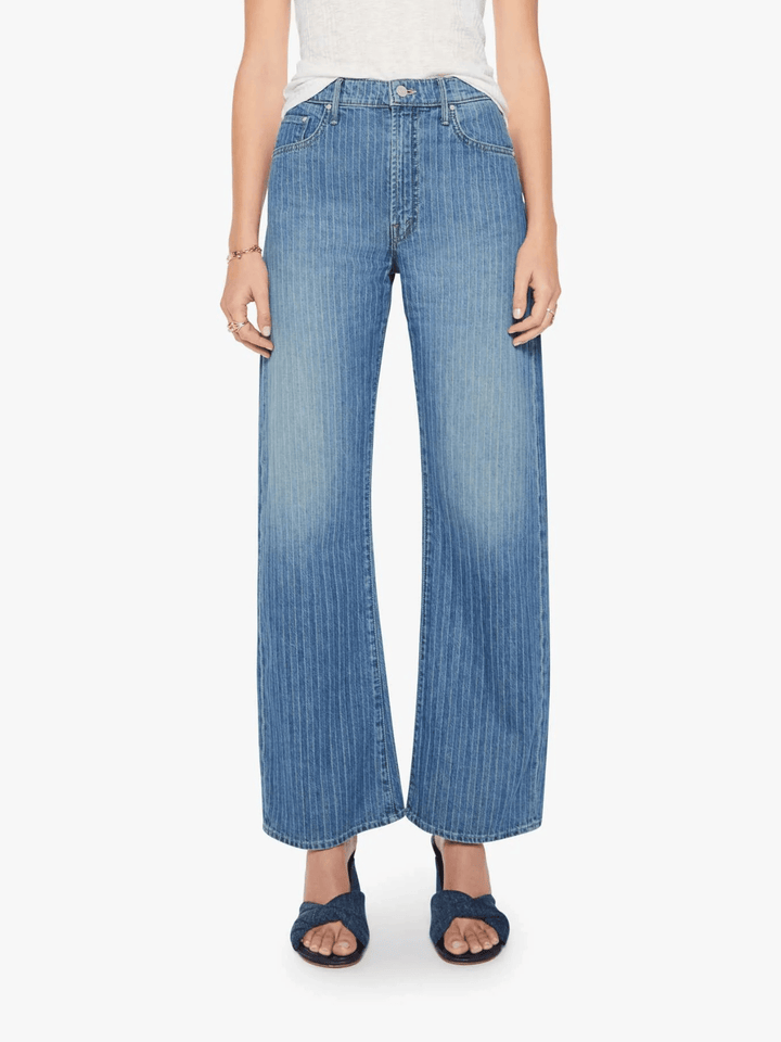 A model wearing a pair of wide-leg cropped blue denim jeans with a vertical pleated texture, paired with a white top and dark blue slide sandals, against a plain white background.