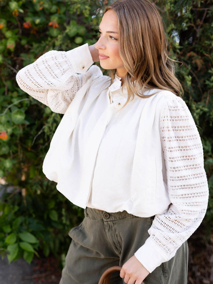 Woman in an Off White Mystree Bubble Hem Jacket with crochet knit sleeves and a gathered elastic hem.