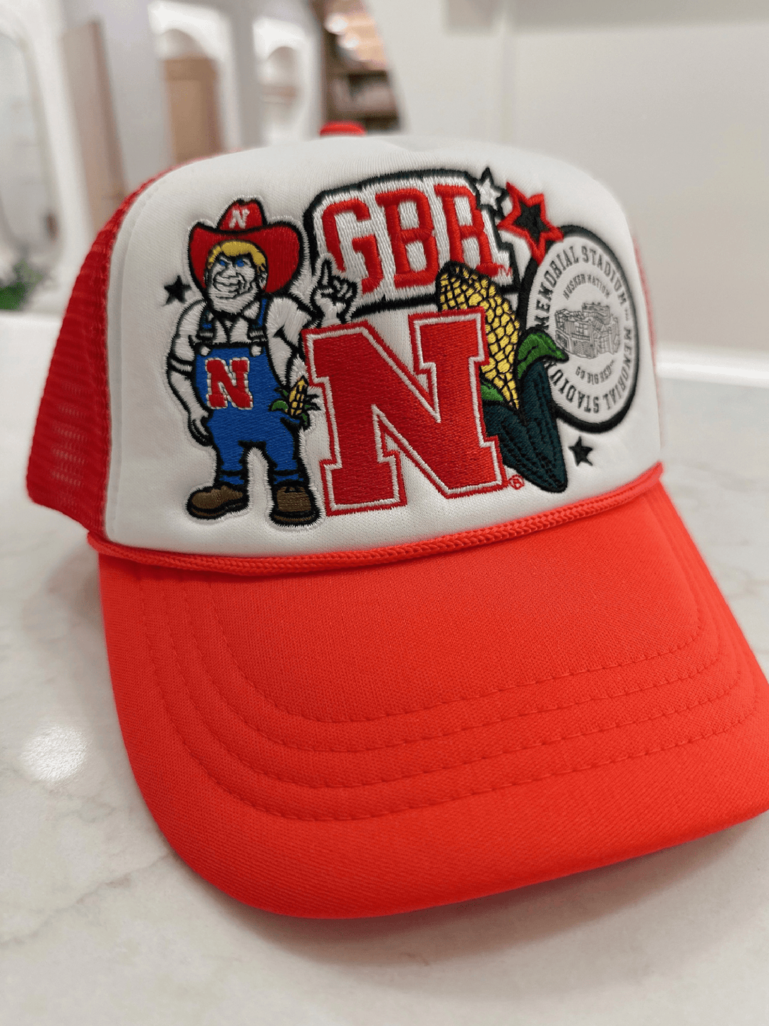 Red and white cap with embroidered design on a marble surface