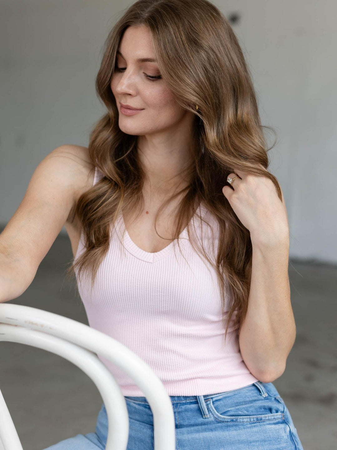 Model wearing a light pink NIKIBIKI reversible ribbed tank top with a scooped v-neckline and blue jeans.
