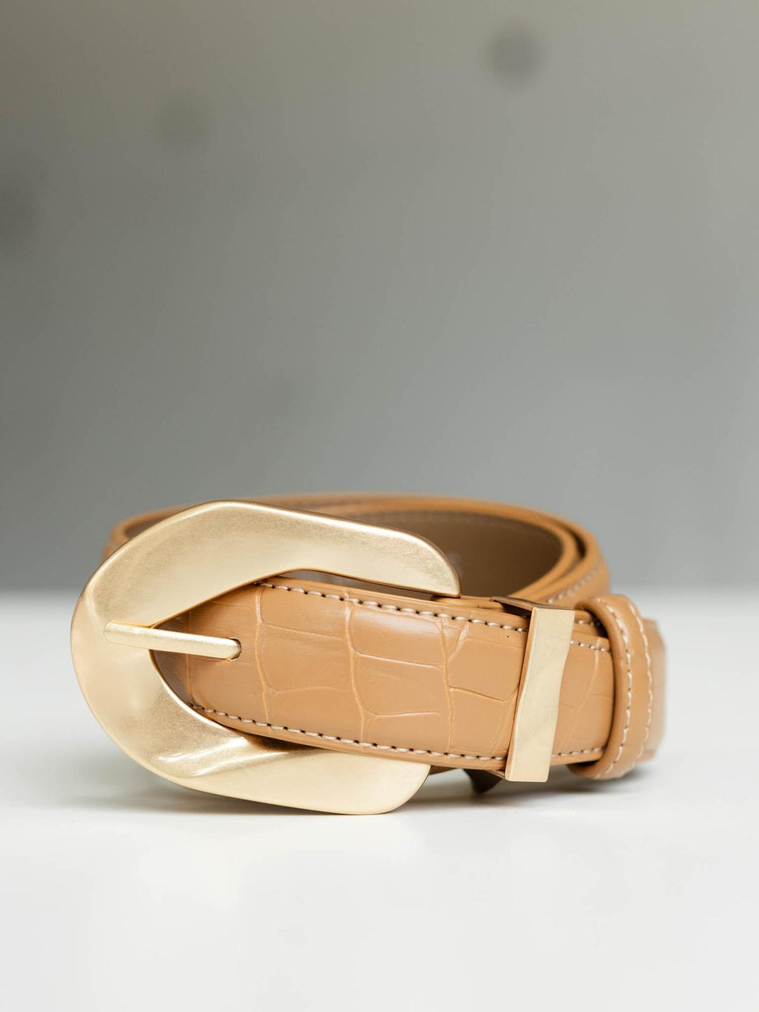 Tan croc-embossed leather belt with a large, gleaming gold buckle.