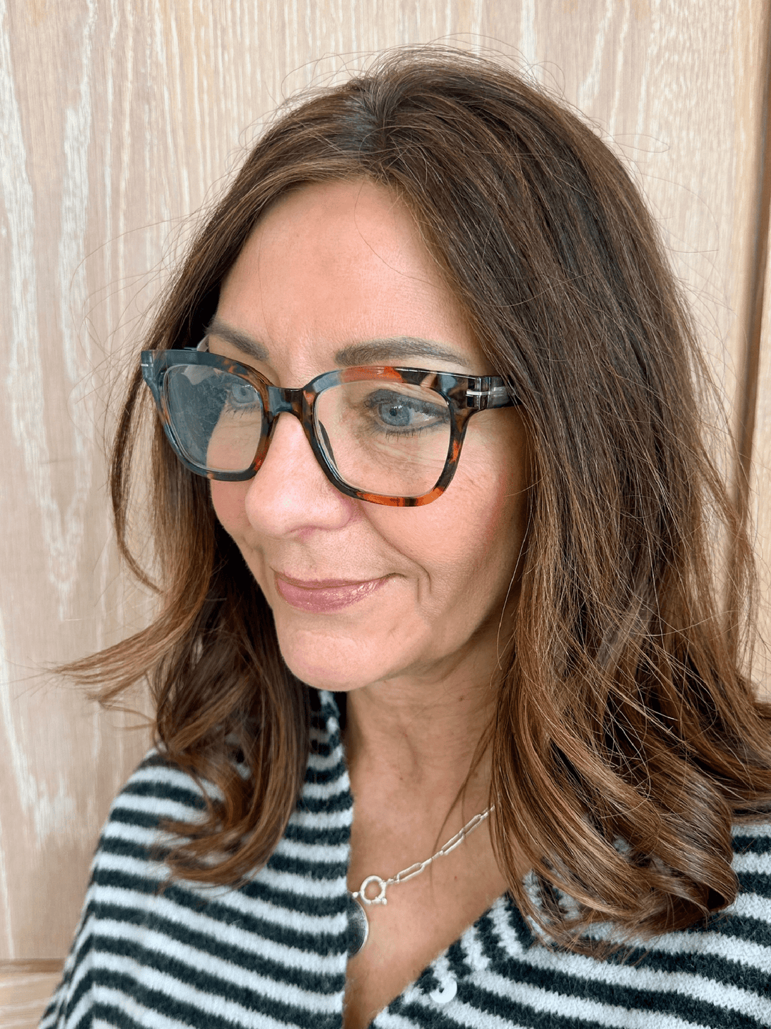 Woman wearing glasses and a striped shirt against a neutral background