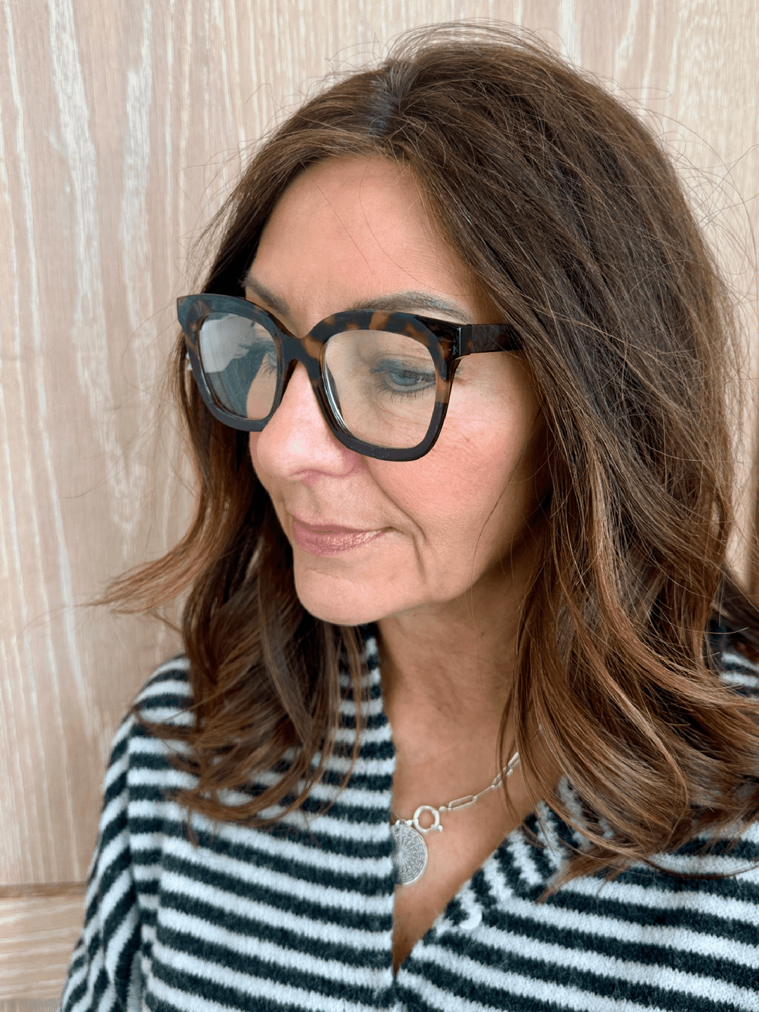 Woman wearing tortoiseshell glasses with a neutral background