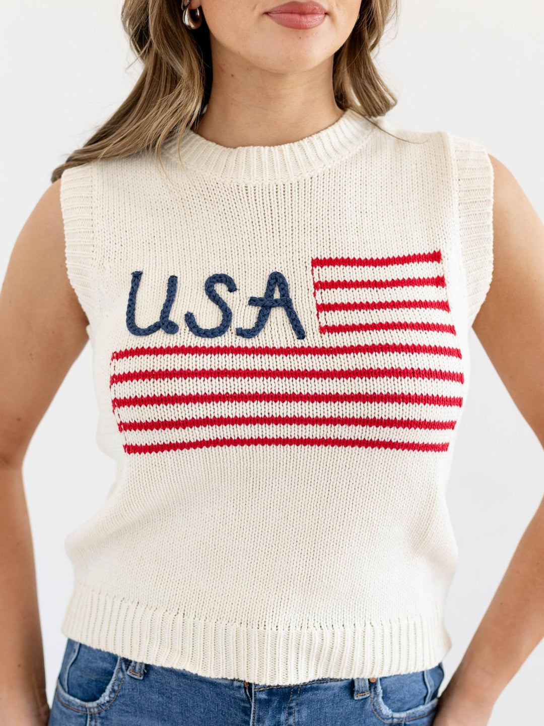 Woman wearing a sleeveless knit sweater with &