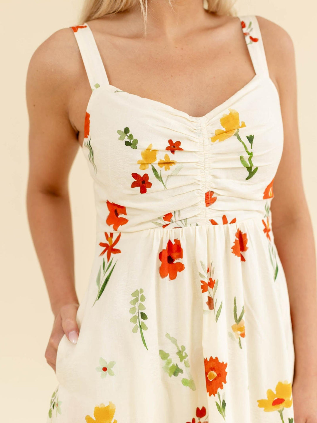 White dress with colorful floral pattern worn by a person on a beige background