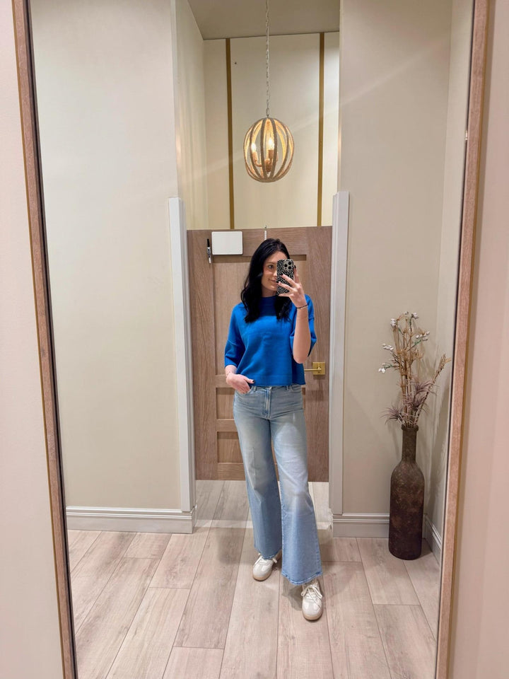 Woman in a blue PINCH Short Sleeve Sweater Top with 3/4 sleeves, relaxed fit, and light wash jeans.