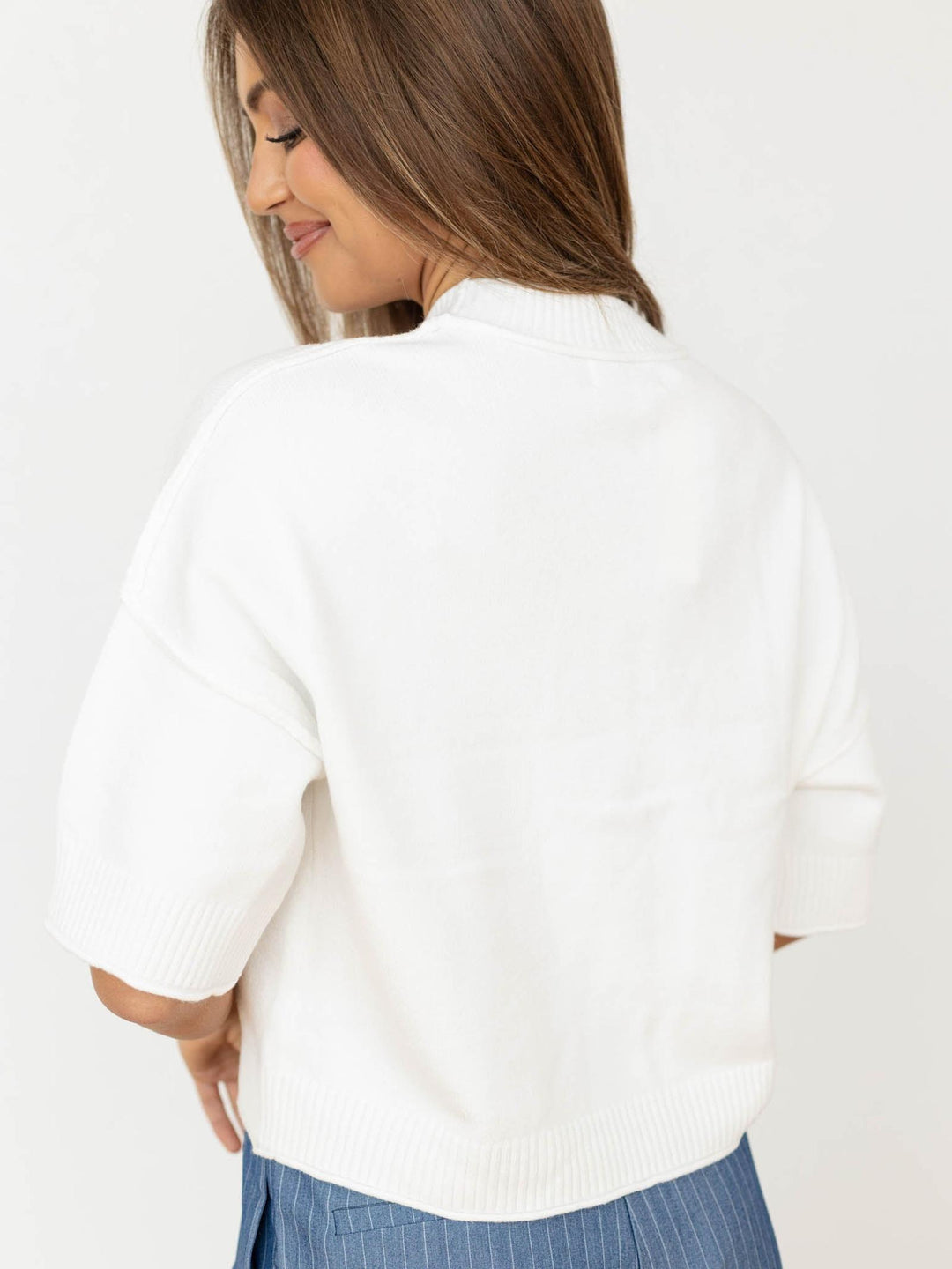 Woman wearing a white sweater with a neutral background