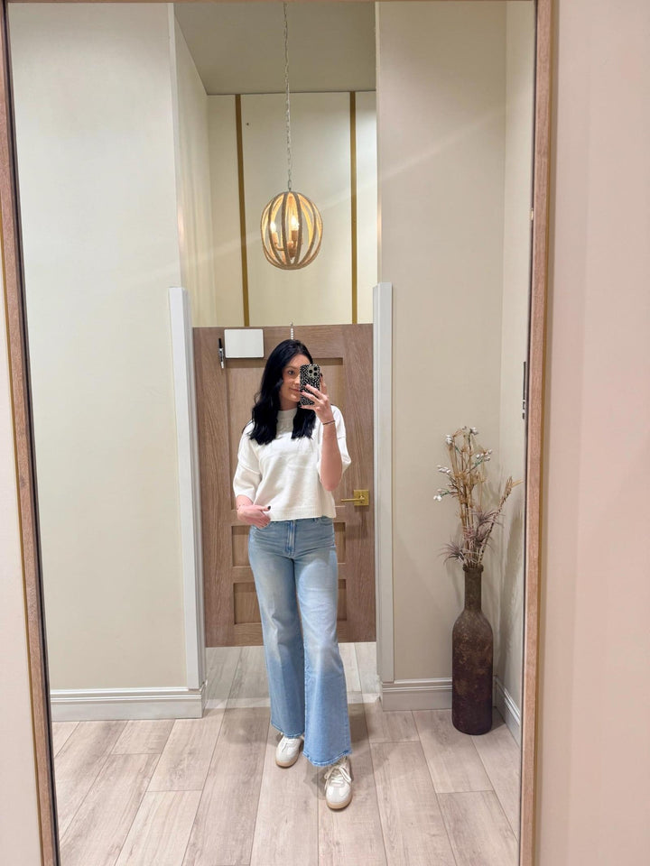 Woman in a white PINCH Short Sleeve Sweater Top with 3/4 sleeves, exposed seams, and rolled hemlines.