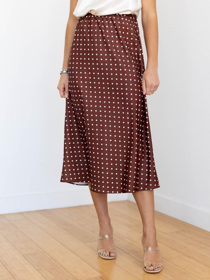 Person wearing a brown polka dot skirt on a plain background