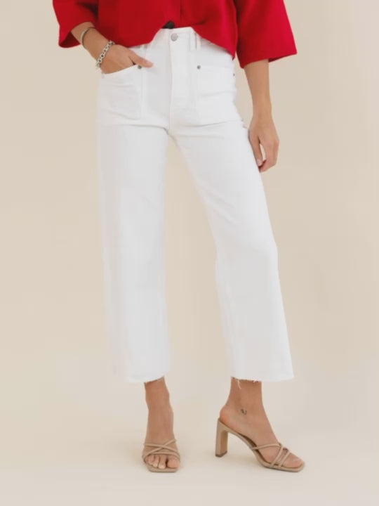 Woman wearing a red jacket and white pants on a beige background
