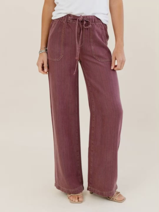 Person wearing maroon wide-leg pants on a beige background