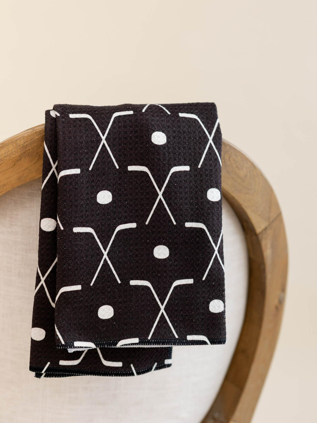Black cotton tea towel with white hockey stick and puck pattern.