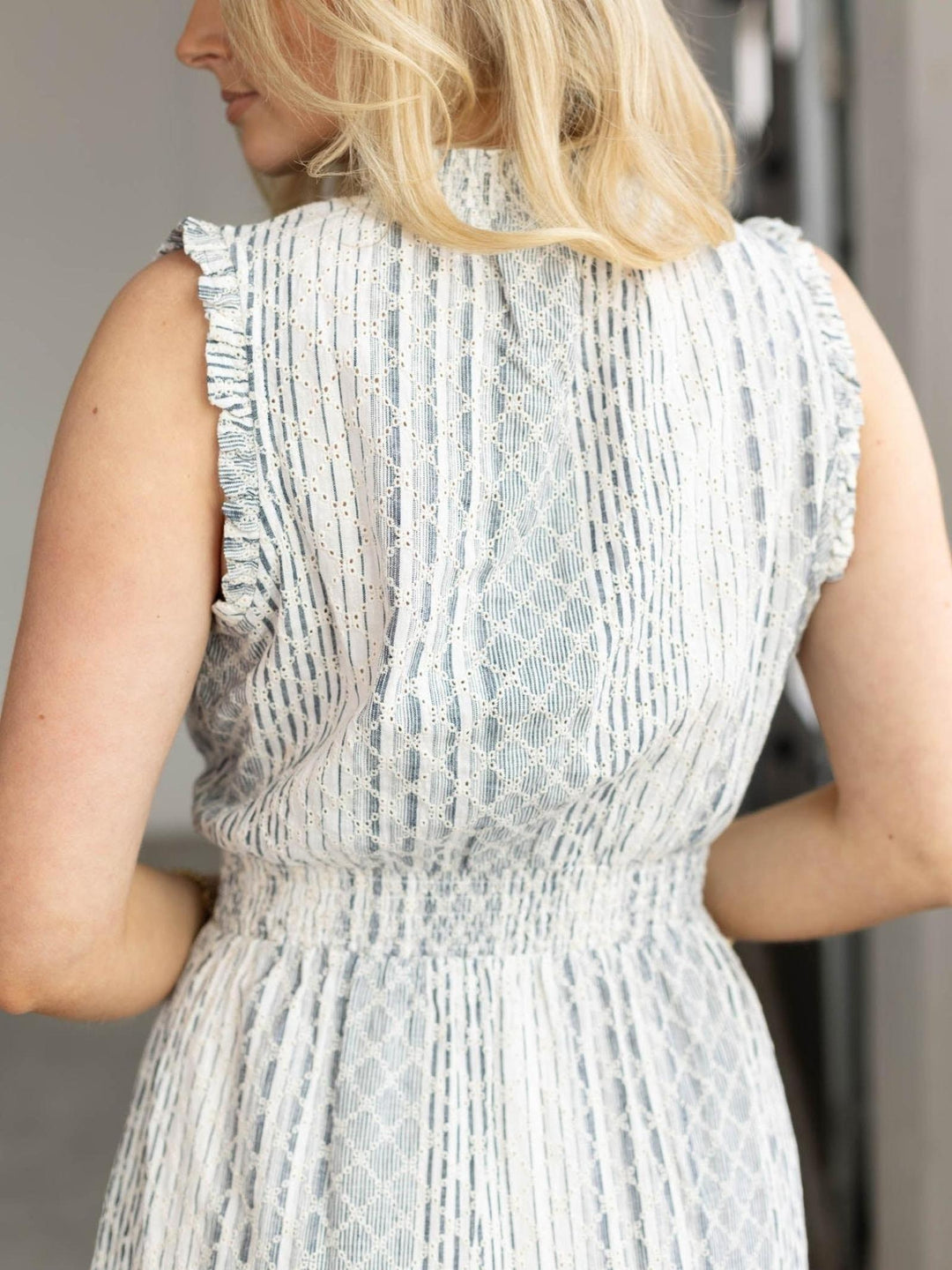 Person wearing a light blue sleeveless dress with textured pattern.