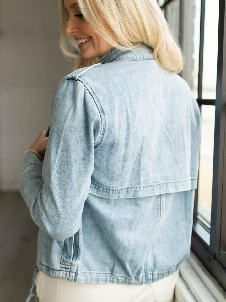 Woman wearing a light blue denim jacket indoors.